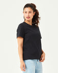 Schwarzes Damen T-Shirt aus hochwertiger Bio-Baumwolle, seitlich getragen von Frau mit hellblauer Jeans. Komfortables Rundhals-Shirt mit kurzen Ärmeln. Perfektes Basic für moderne Casual Styles und nachhaltige Damenmode