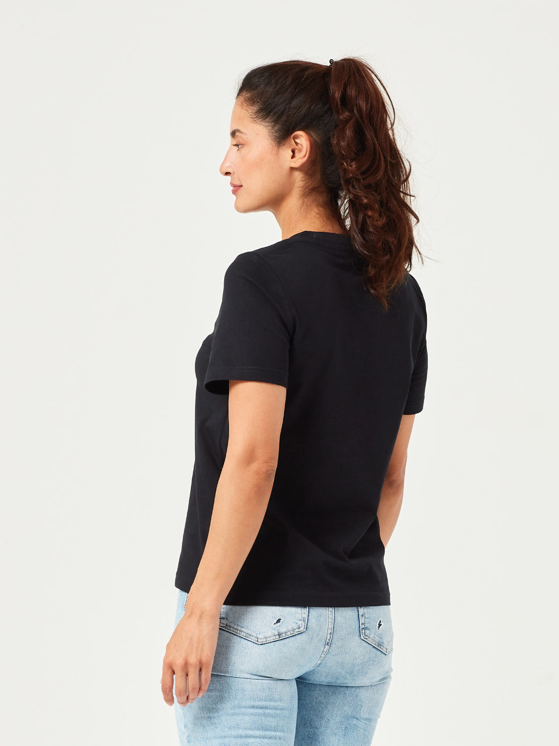 Frau trägt ein minimalistisches schwarzes Damen T-Shirt aus nachhaltiger Bio-Baumwolle. Komfortables Basic-Shirt mit Rundhalsausschnitt, perfekt kombiniert mit hellblauer Jeans. Ideal für Freizeit, Casual Outfits und moderne Streetwear.