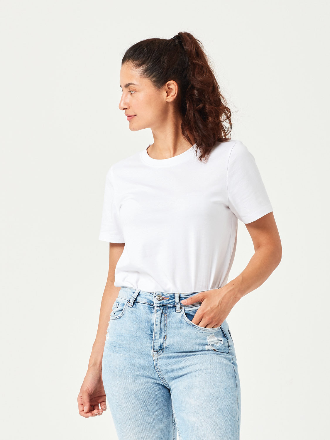 Weißes Damen T-Shirt aus hochwertiger Bio-Baumwolle, in der Hose gesteckt getragen von Frau mit hellblauer Jeans. Komfortables Rundhals-Shirt mit kurzen Ärmeln. Perfektes Basic für moderne Casual Styles und nachhaltige Damenmode.