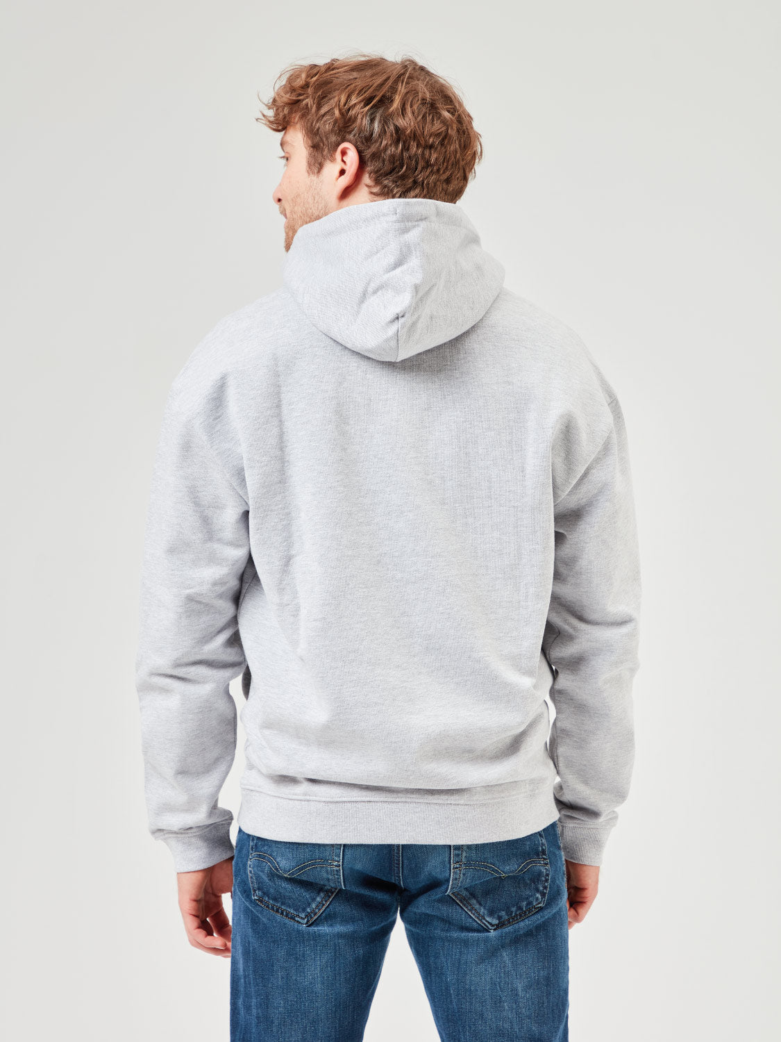 Rückansicht eines Mannes der einen grau melangen Unisex Hoodie aus Bio-Baumwolle mit Kapuze und Kängurutaschen trägt. Kombiniert mit blauen Jeans für lässige Freizeitlooks und moderne Streetwear. Nachhaltige Mode für Männer.