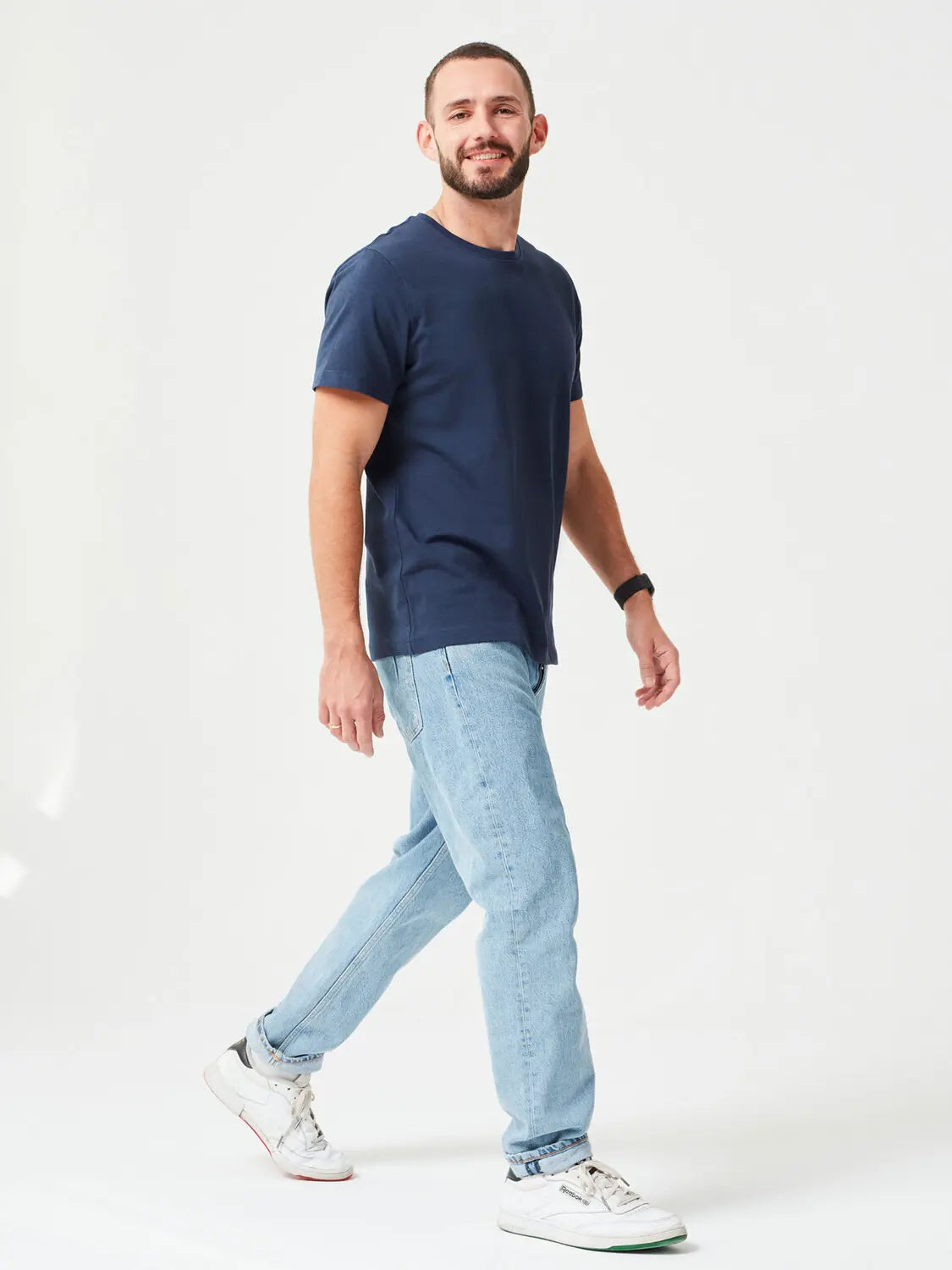 Mann trägt hochwertiges Premium T-Shirt aus 280 GSM Bio-Baumwolle in Navy mit blauer Hose uns weißen Sneakern. Nachhaltiges, dickes T-Shirt mit Rundhalsausschnitt, perfekt für moderne Casual Outfits und umweltfreundliche Mode.