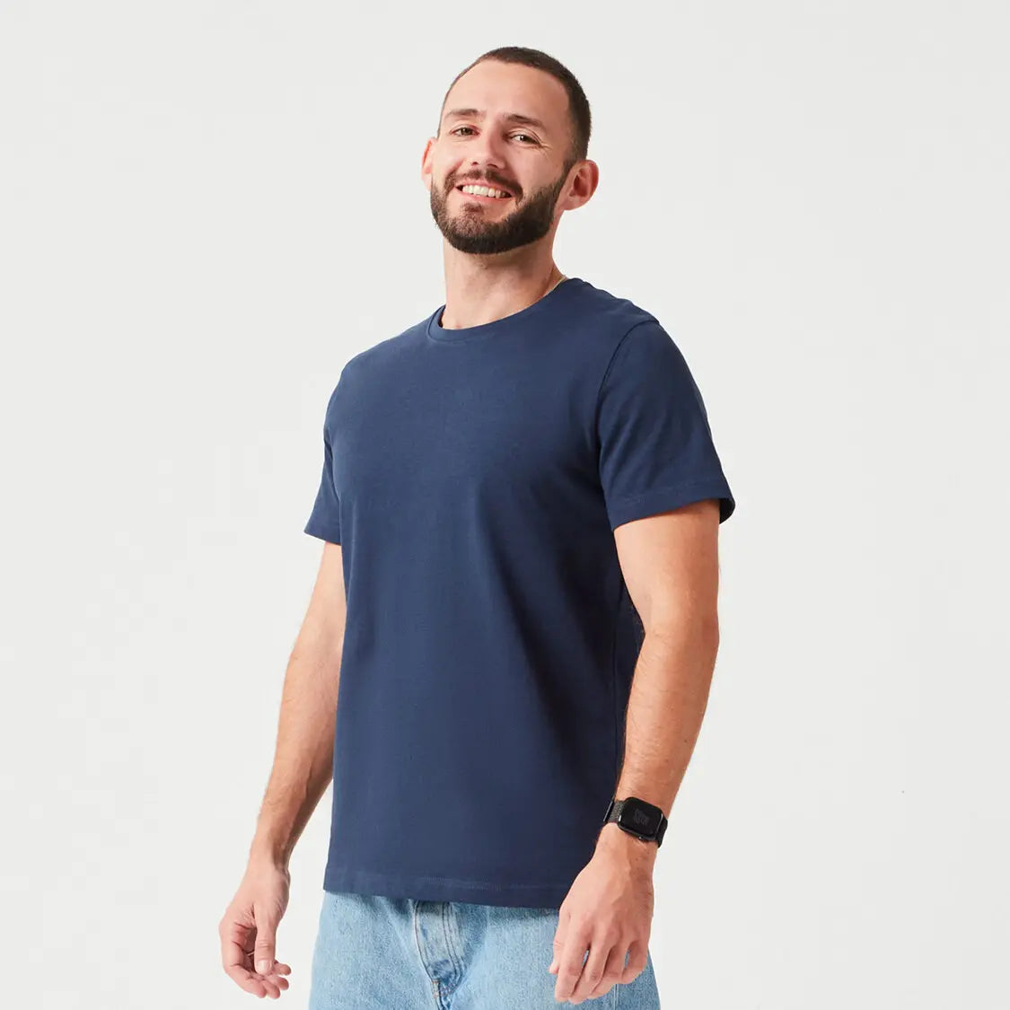 Mann trägt Navy farbenes Premium T-Shirt aus 280 GSM Bio-Baumwolle. Hochwertiges, umweltfreundliches Basic-Shirt mit Rundhalsausschnitt, ideal für lässige Alltagsoutfits.